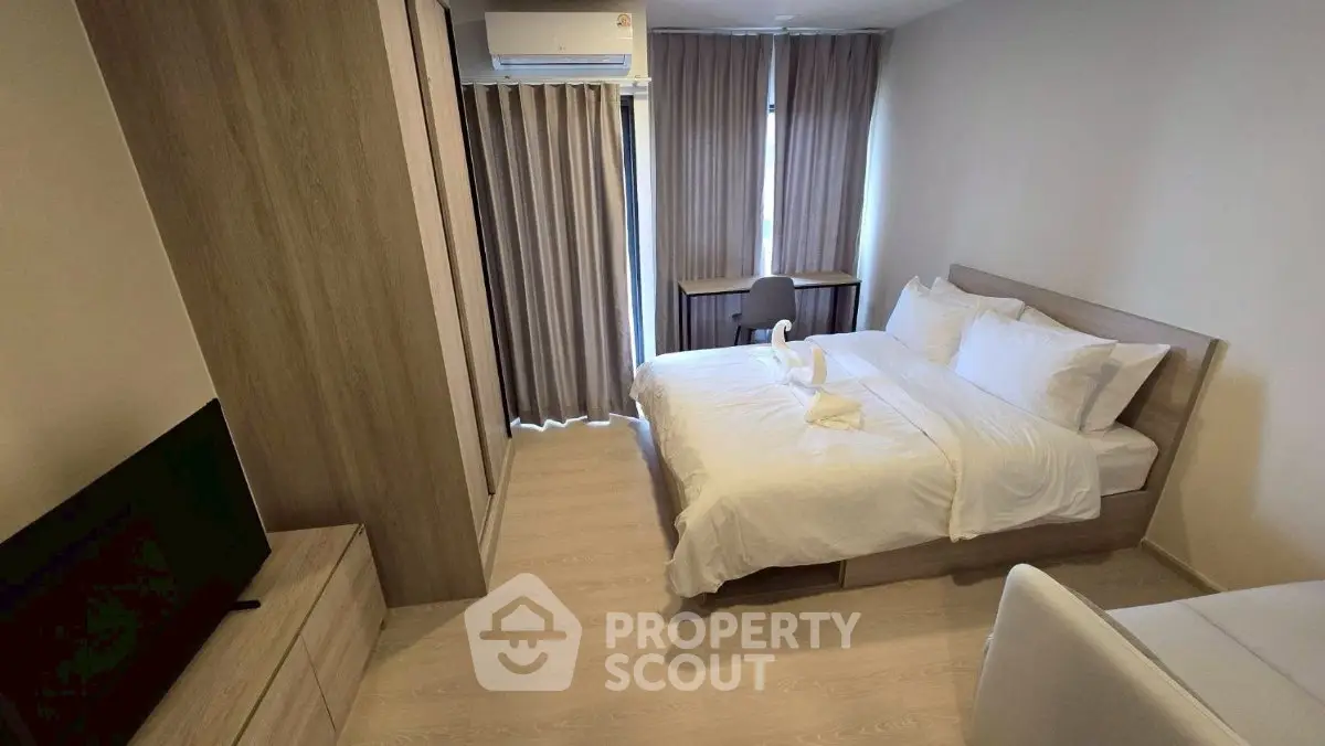 Modern bedroom with cozy bed, TV, and stylish decor in a well-lit apartment.