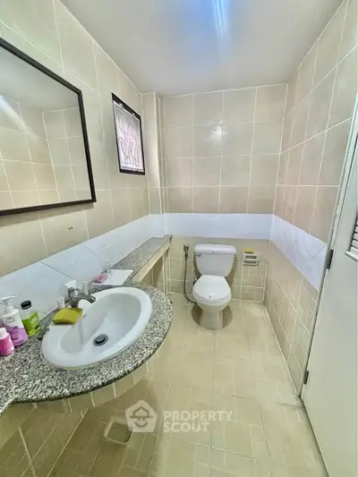 Modern bathroom with granite countertop and tiled walls in a real estate property.