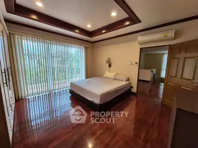 Spacious bedroom with wooden flooring and large windows in a modern home.
