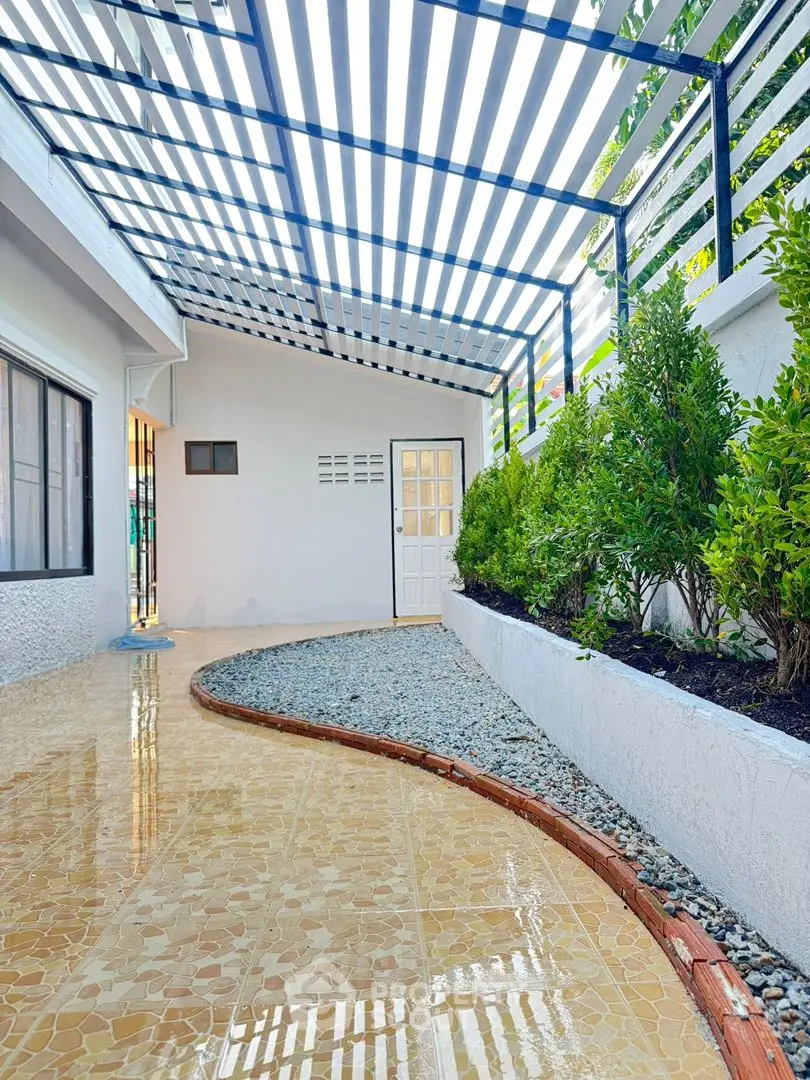 Charming exterior walkway with modern pergola and lush greenery