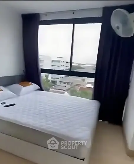 Cozy bedroom with large window offering city view, perfect for relaxation and comfort.