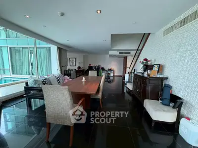 Luxurious open-plan living room with elegant dining area and pool view, perfect for modern living.