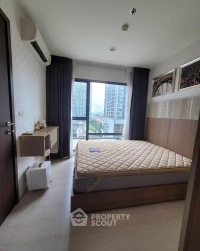 Modern bedroom with large window and city view, featuring stylish decor and ample natural light.