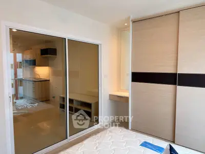 Modern bedroom with sliding glass doors and built-in wardrobe in a stylish apartment.