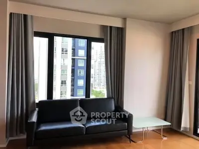 Modern living room with black leather sofa and city view window