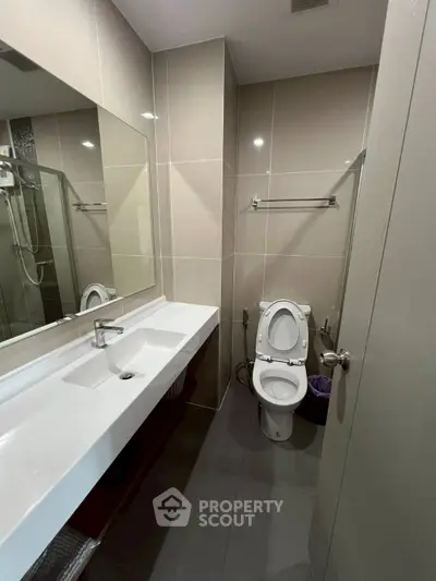 Modern bathroom with sleek fixtures and large mirror in a contemporary apartment.