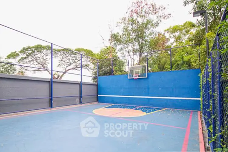 Outdoor basketball court surrounded by lush greenery, perfect for sports enthusiasts.