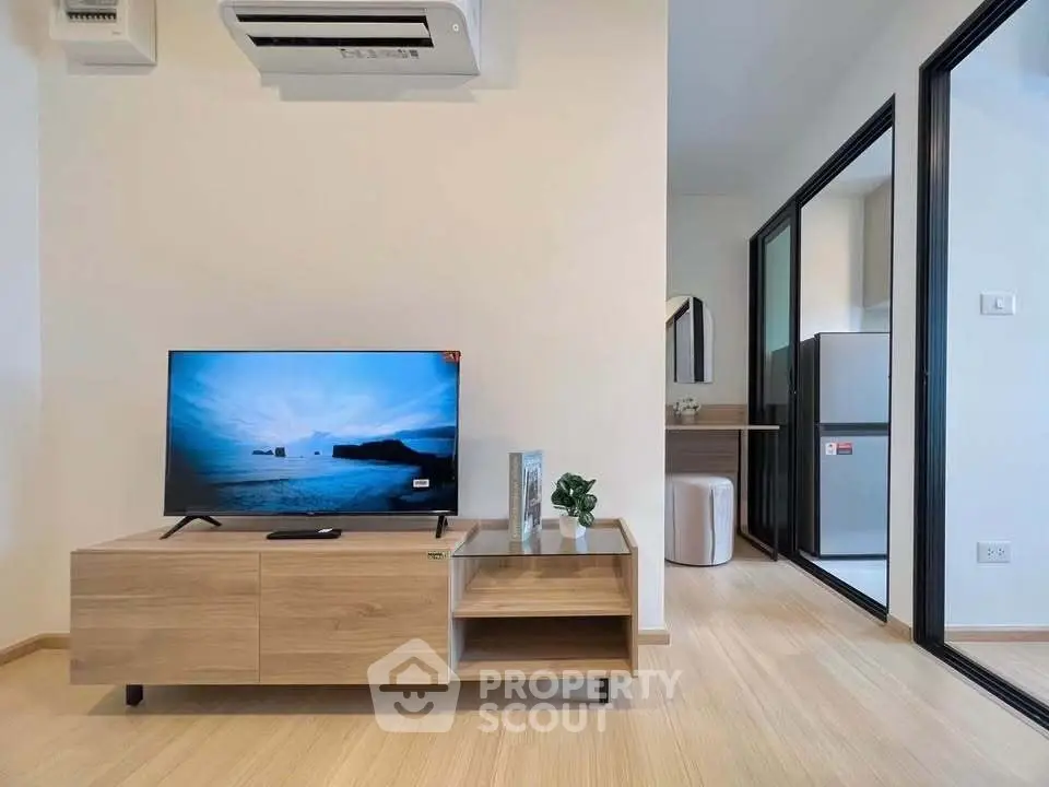 Modern living room with sleek TV setup and open kitchen layout in stylish apartment.
