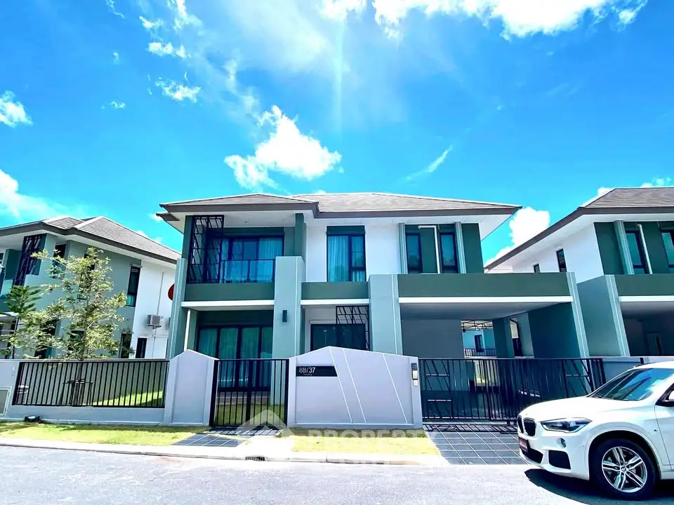 Modern two-story house with sleek design and spacious driveway under a clear blue sky.