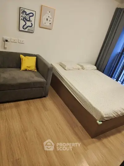 Cozy bedroom with wooden flooring, compact sofa, and modern decor.