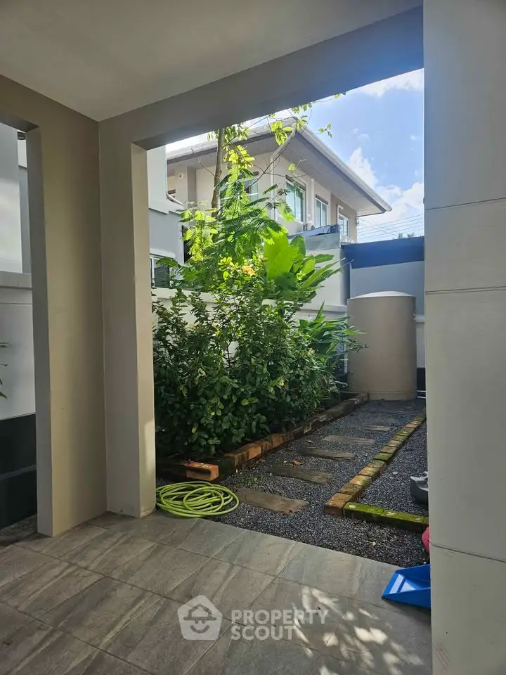 Charming garden view from a modern residential property with lush greenery and paved pathway.