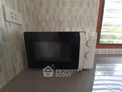 Modern kitchen with sleek microwave on countertop and stylish tiled backsplash.