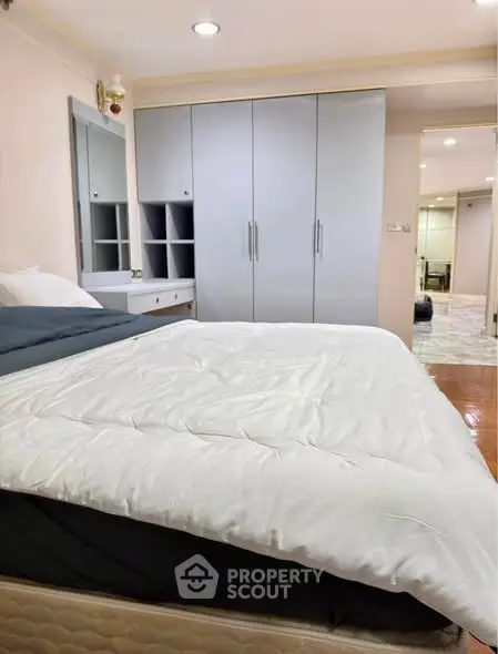 Spacious bedroom with modern wardrobe and cozy bedding in a stylish apartment.