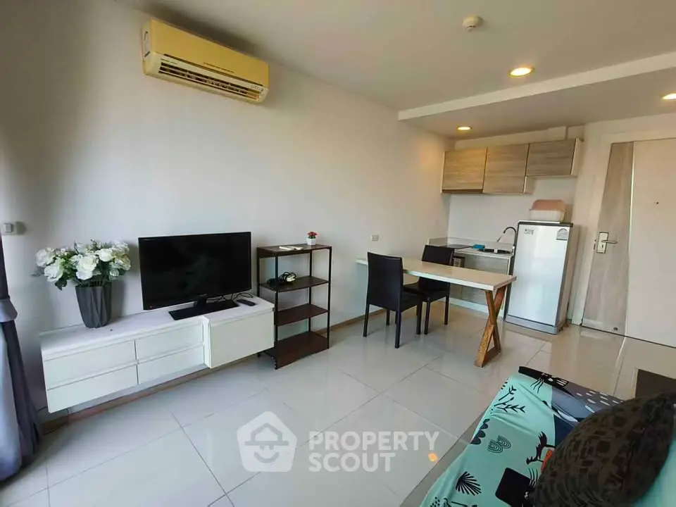 Modern living room with sleek furniture and compact kitchen in open layout apartment.