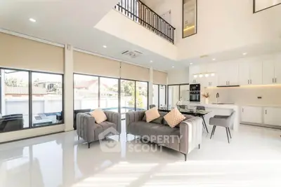 Spacious modern living room with high ceilings and large windows, featuring elegant furniture and abundant natural light.