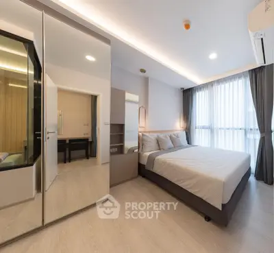 Modern bedroom with sleek design, large mirrored wardrobe, and natural light from floor-to-ceiling windows.