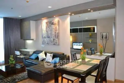 Modern living room with stylish decor and dining area, featuring a cozy sectional sofa and elegant lighting.