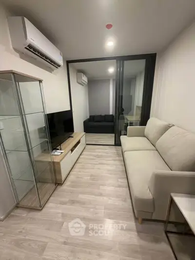 Modern living room with sleek glass cabinet and cozy sofa in a stylish apartment.