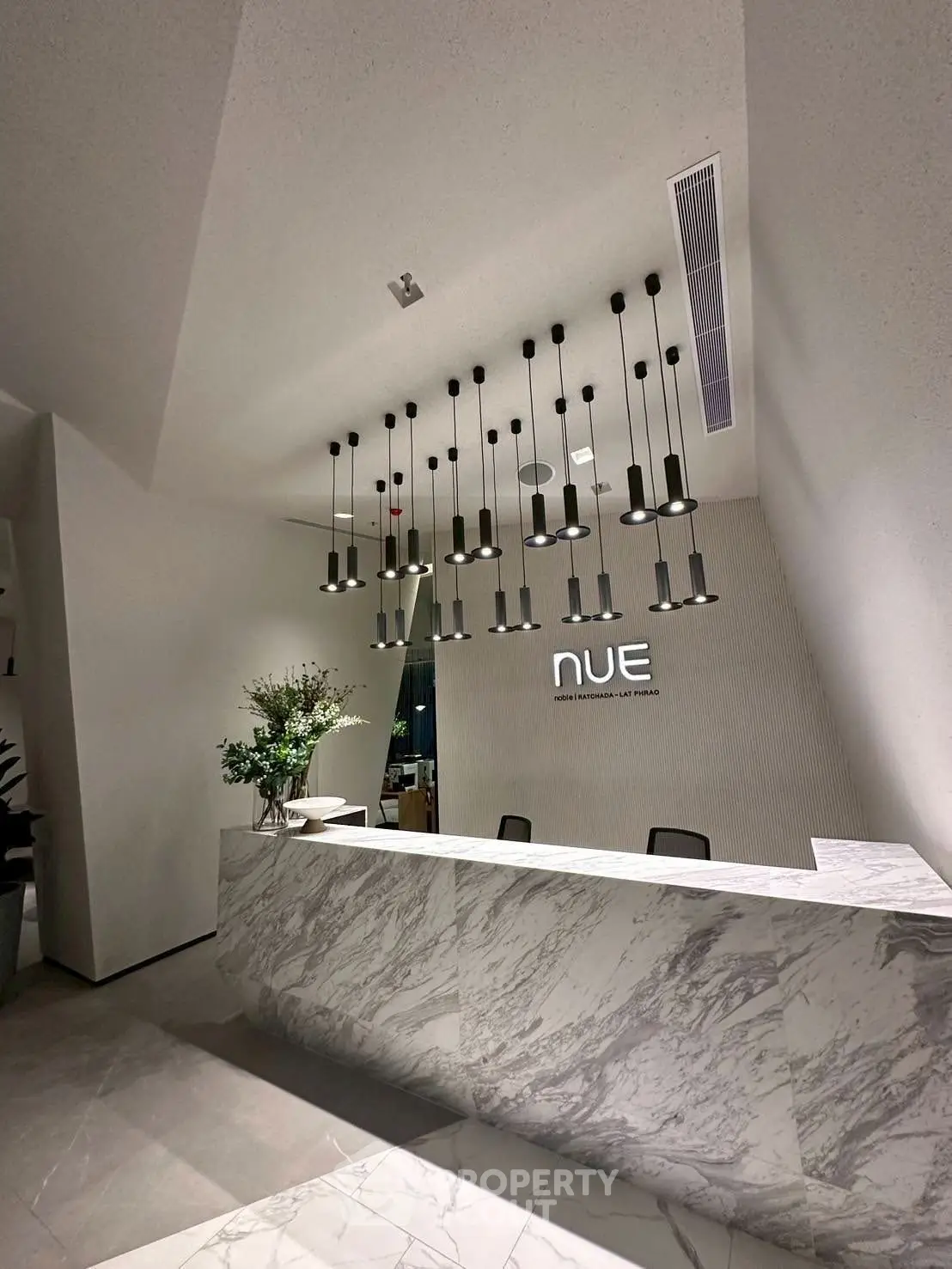 Elegant modern reception area with marble desk and stylish pendant lighting in a luxury building.