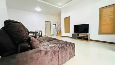 Spacious modern living room with plush sofa and flat-screen TV, ideal for relaxation and entertainment.