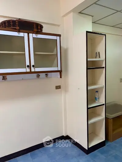 Compact kitchen with white cabinets and blue tile flooring, featuring open shelving for storage.