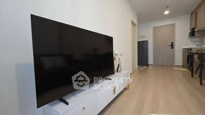 Modern living room with sleek TV and stylish kitchen in open layout apartment.