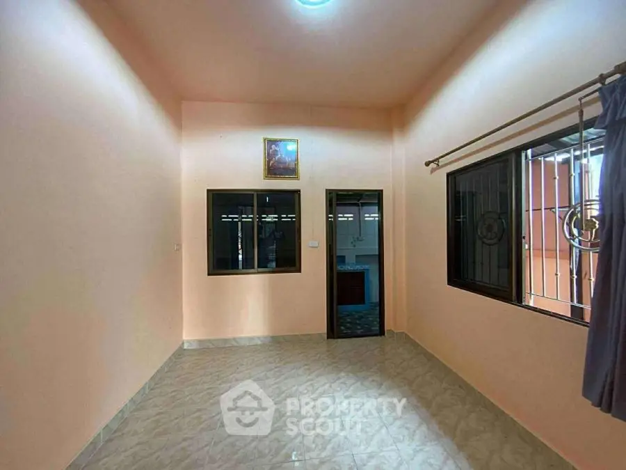 Spacious empty room with tiled floor and large windows, ideal for customization.
