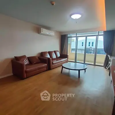 Spacious living room with leather sofas and balcony view in modern apartment