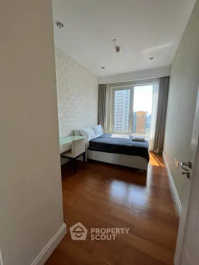 Modern bedroom with city view, wooden flooring, and elegant decor in a high-rise apartment.