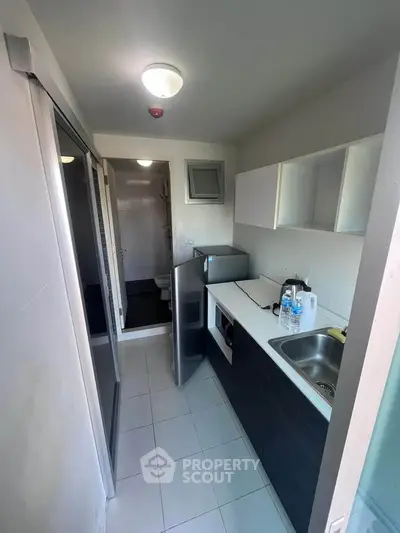 Compact modern kitchen with sleek cabinetry and appliances in a narrow layout.