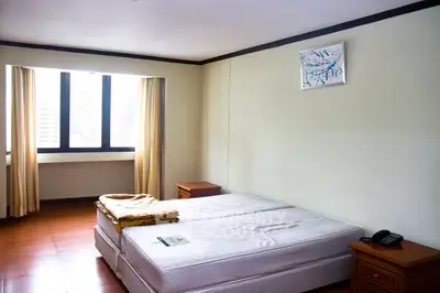 Spacious bedroom with large window and minimalistic decor in urban apartment.