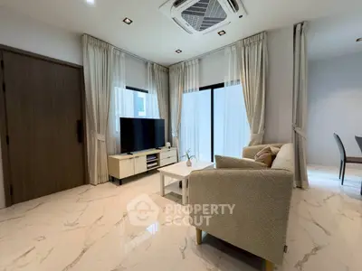 Modern living room with elegant decor and natural light, featuring a cozy sofa and large TV.