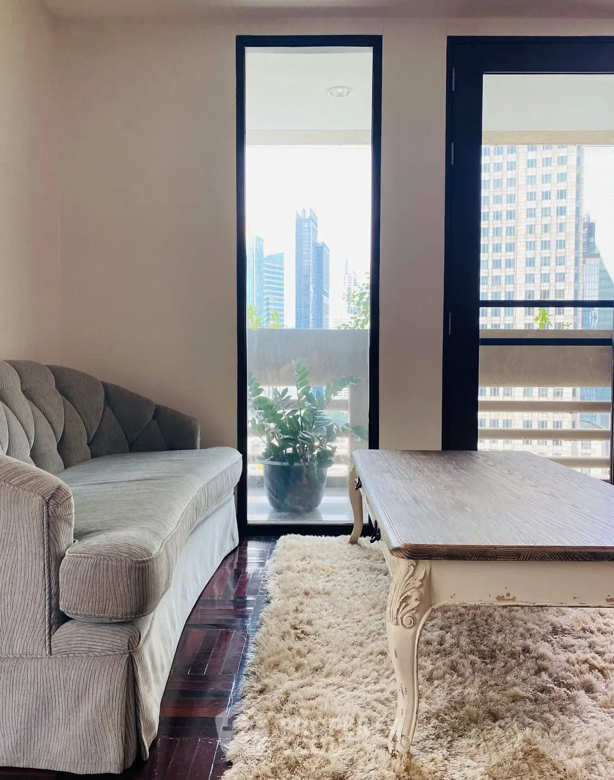 Chic living room with plush sofa, elegant coffee table, and city view balcony.