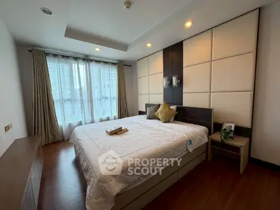 Spacious bedroom with modern decor and large window offering city views.