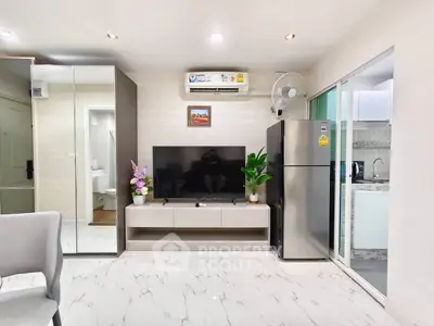 Modern living room with sleek TV setup and stainless steel fridge, showcasing contemporary interior design.