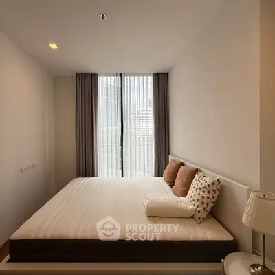 Cozy bedroom with large window and city view, featuring modern decor and neutral tones.