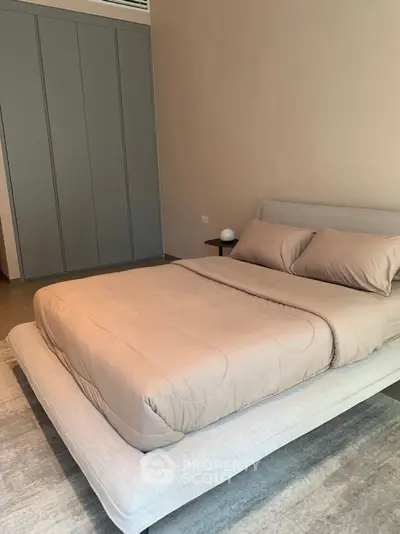 Modern bedroom with sleek design and neutral tones, featuring a comfortable bed and built-in wardrobe.