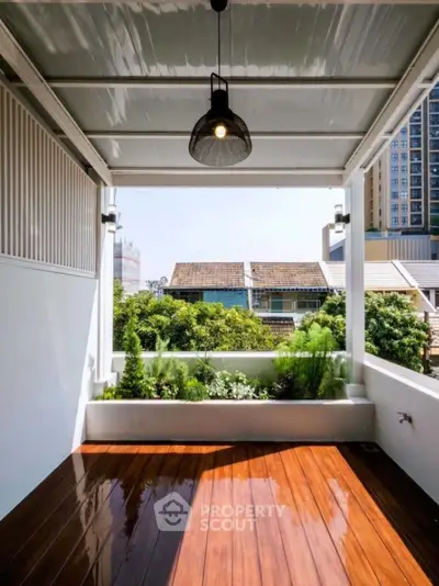 Charming balcony with wooden flooring and lush greenery view in modern urban setting.