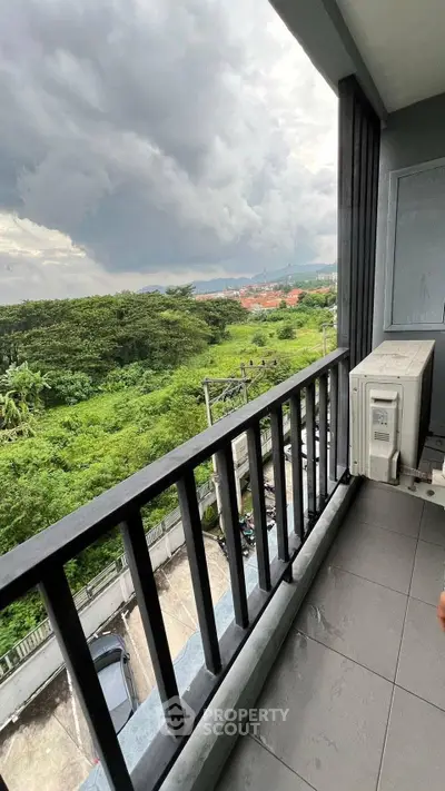 Spacious balcony with lush green view and air conditioning unit, perfect for relaxation.