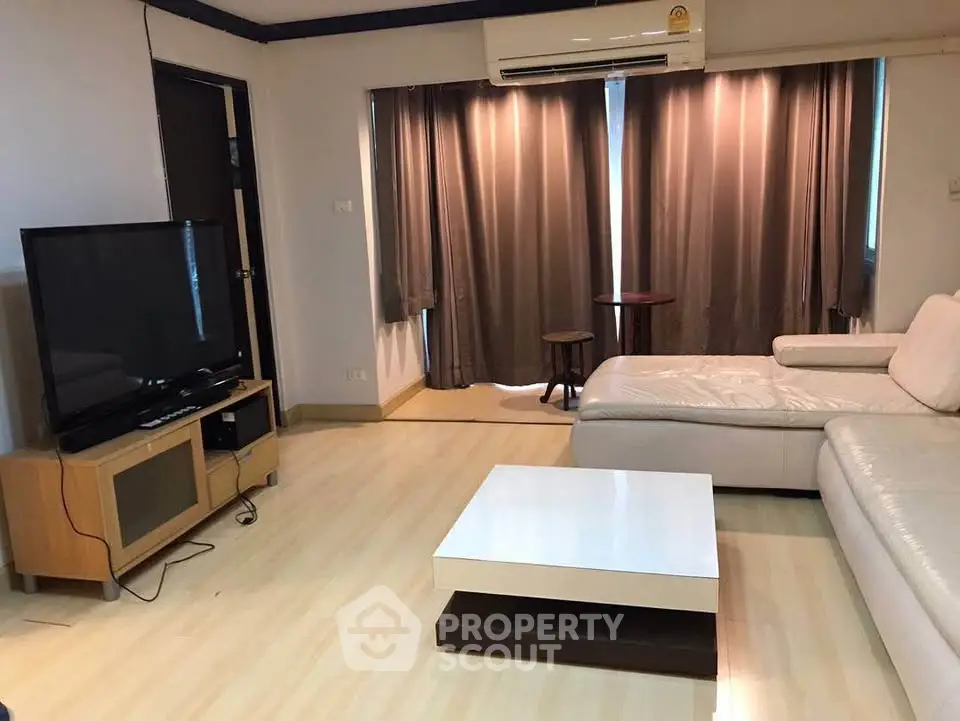 Spacious living room with modern furniture and large TV, perfect for relaxation.