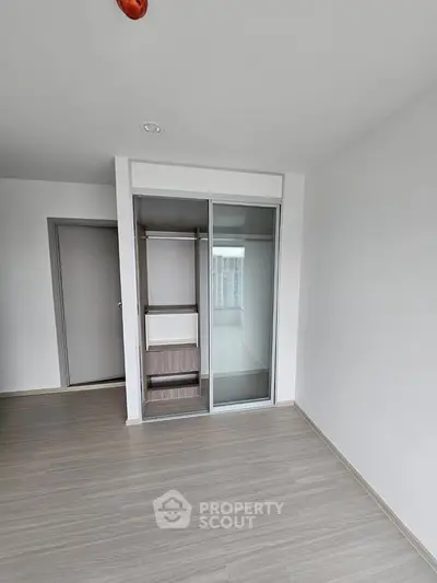 Modern minimalist bedroom with sliding closet doors and light wood flooring.