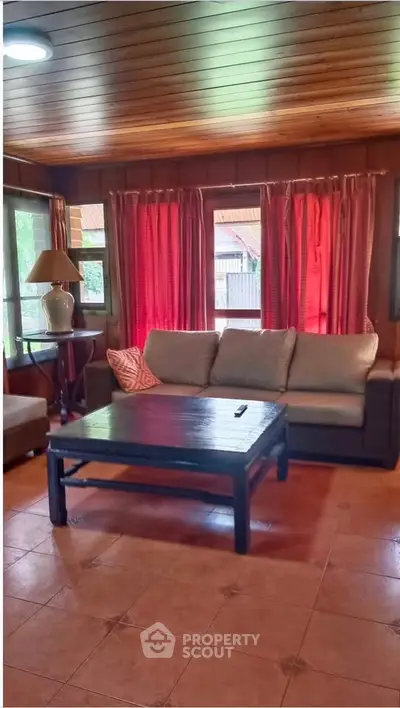 Cozy living room with wooden ceiling, large windows, and comfortable seating.