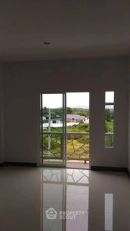 Spacious room with large windows offering a serene view of greenery, perfect for natural light lovers.