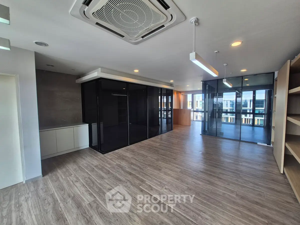 Spacious modern living room with glass partitions and wooden flooring