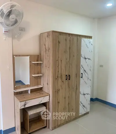 Modern bedroom with stylish wooden wardrobe and vanity set, featuring a wall-mounted fan for comfort.