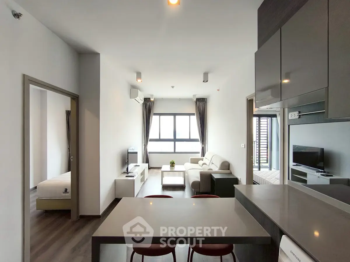 Modern open-layout living room with sleek kitchen and cozy bedroom in a stylish apartment.