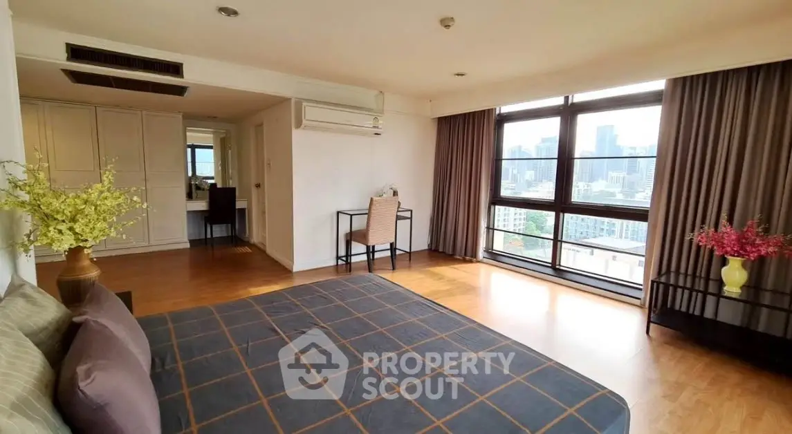 Spacious bedroom with city view and elegant decor in modern apartment.