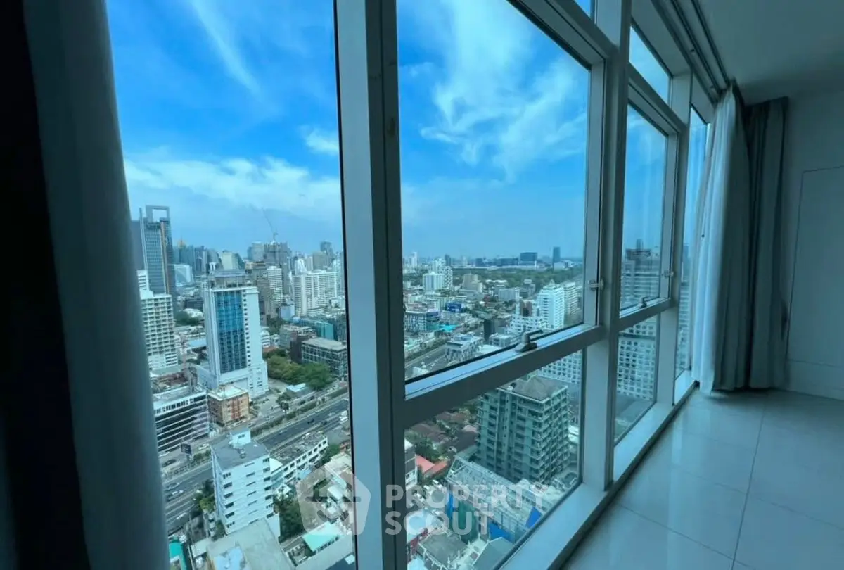 Stunning cityscape view from high-rise apartment window with clear blue sky.