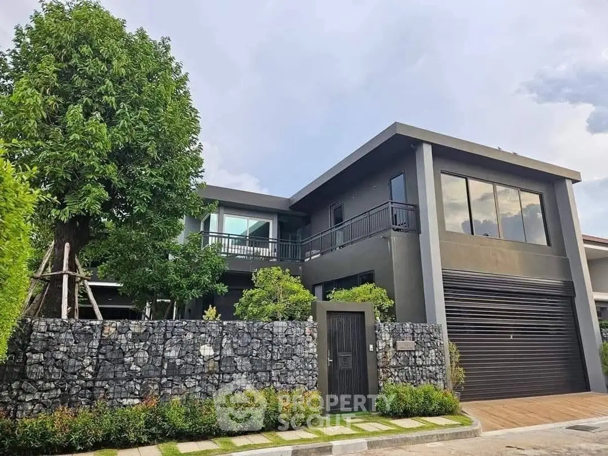 Modern two-story house with large windows and lush greenery