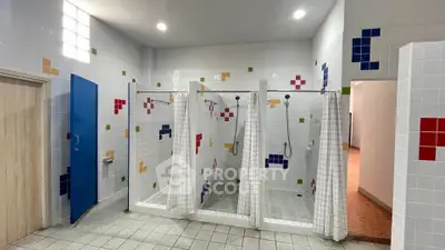 Spacious communal shower area with colorful tiled walls and modern fixtures.